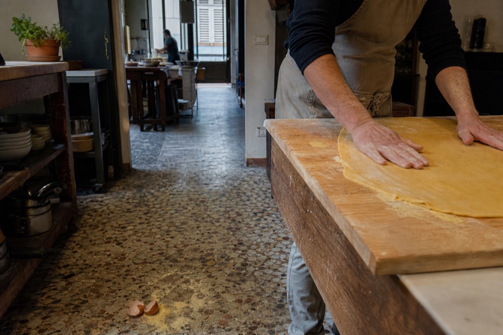 Hands shaping fresh egg pasta dough on a floured wooden board, no text, no logos, no people