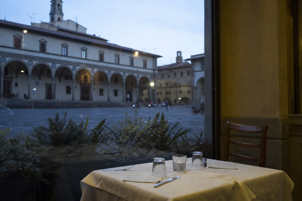 A Florence restaurant table set for dinner in early evening with empty street outside, no text, no logos, no people