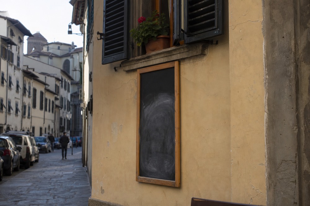 A chalkboard menu on a Florence restaurant wall with handwritten dishes, no text, no logos, no people
