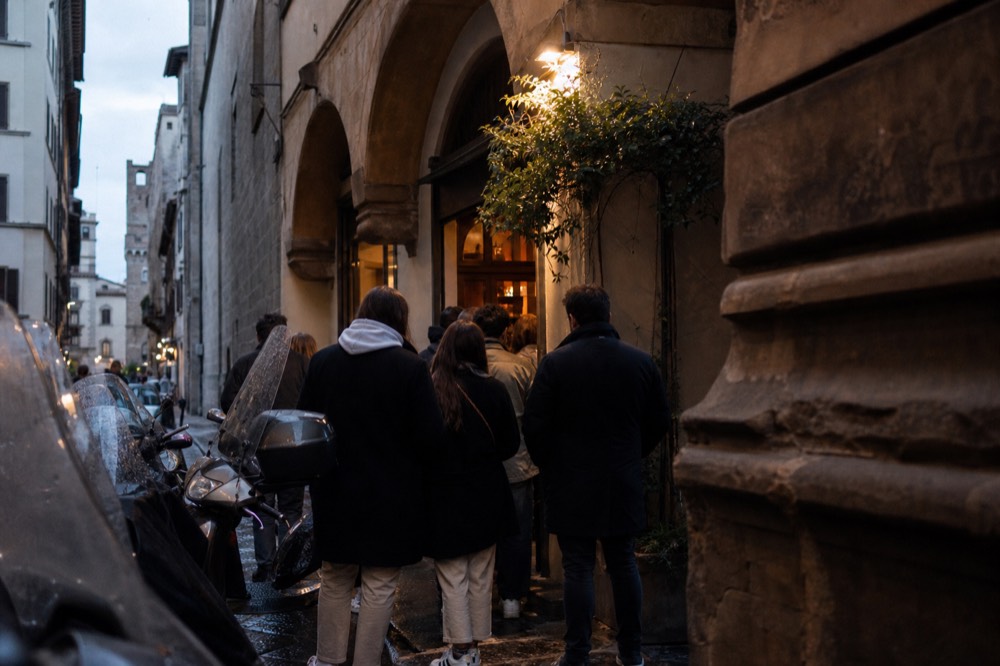 A short queue of people outside a small Florence eatery in the evening, no text, no logos, no people