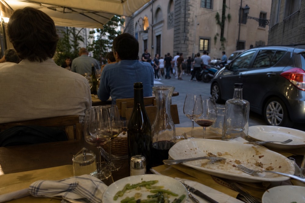 Wooden tables set for dinner in a crowded Florentine trattoria, no text, no logos, no people