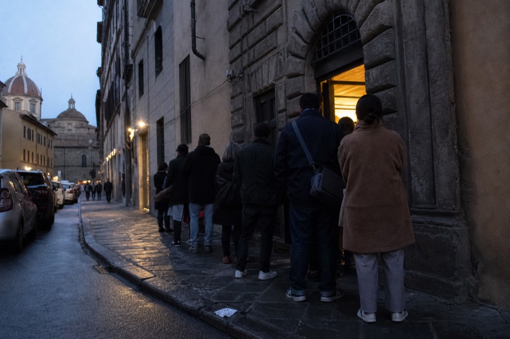 Queue of people waiting outside a restaurant entrance on a Florence street, no text, no logos, no people