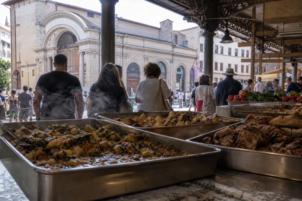 A market food counter with trays of Tuscan dishes at midday, no text, no logos, no people