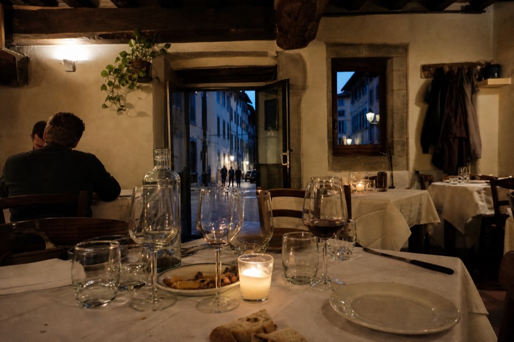 A set dinner table in a Florentine restaurant with wine glasses at evening, no text, no logos, no people