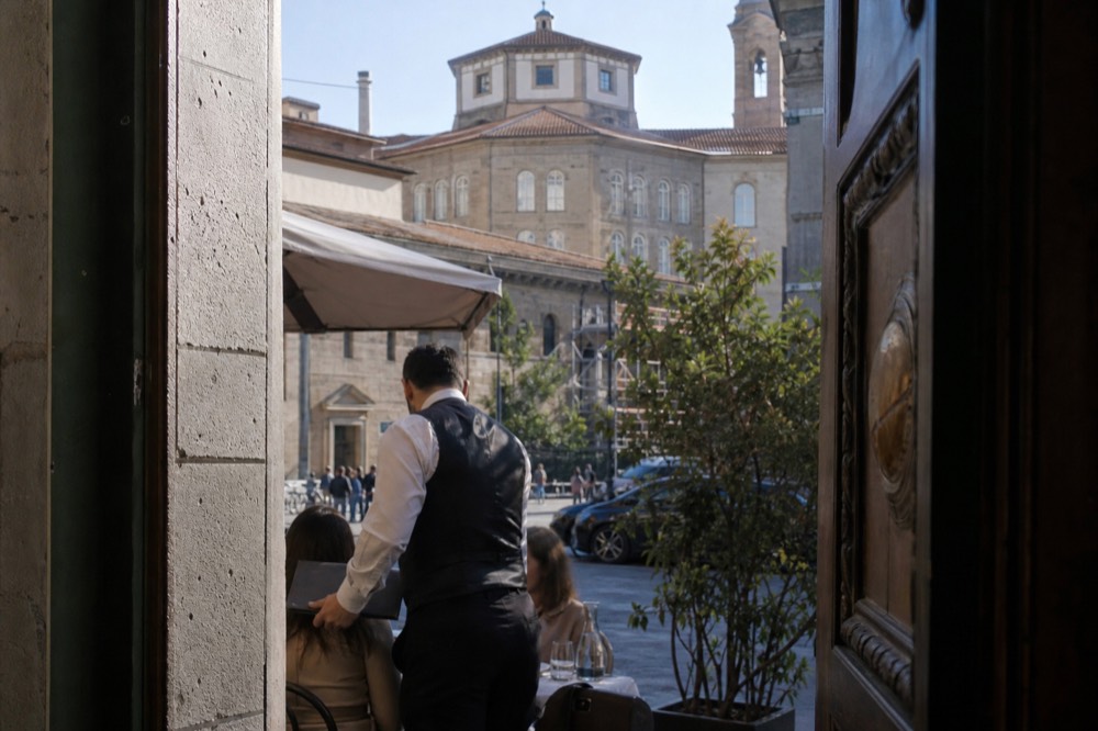 A waiter in a Florence trattoria presenting the bill, no text, no logos, no people
