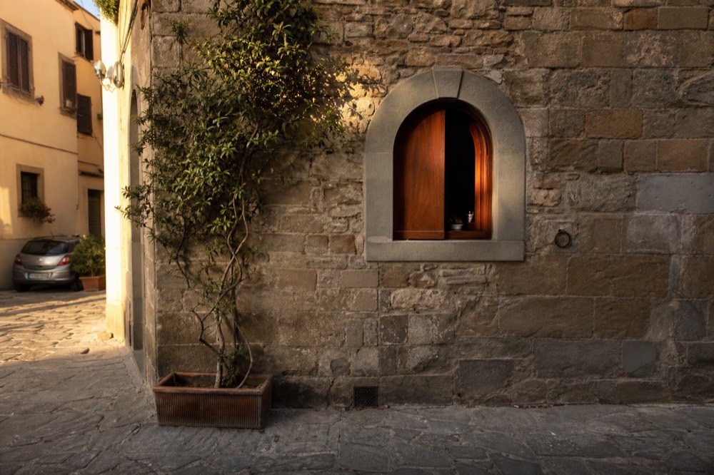 A restored wine window in a Florence stone wall with a small wooden shutter, no text, no logos, no people