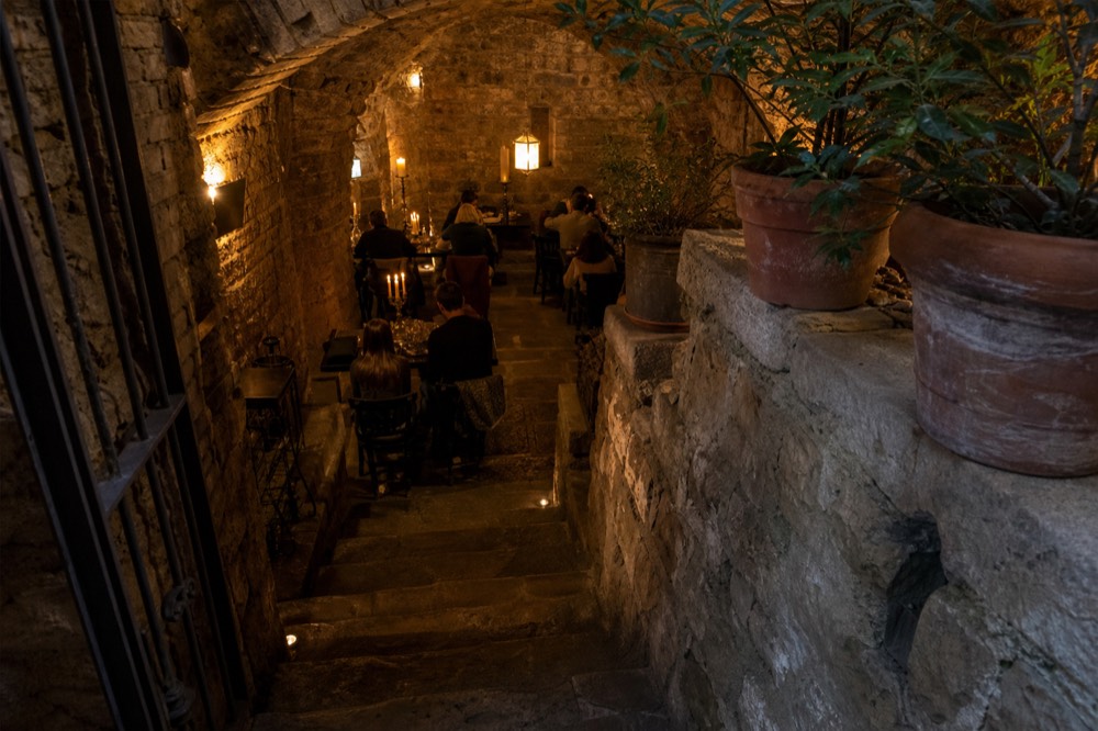 A vaulted stone cellar dining room with candlelit tables in old Florence, no text, no logos, no people