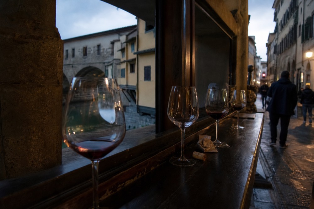 A row of wine glasses on a wooden bar counter in low light, no text, no logos, no people
