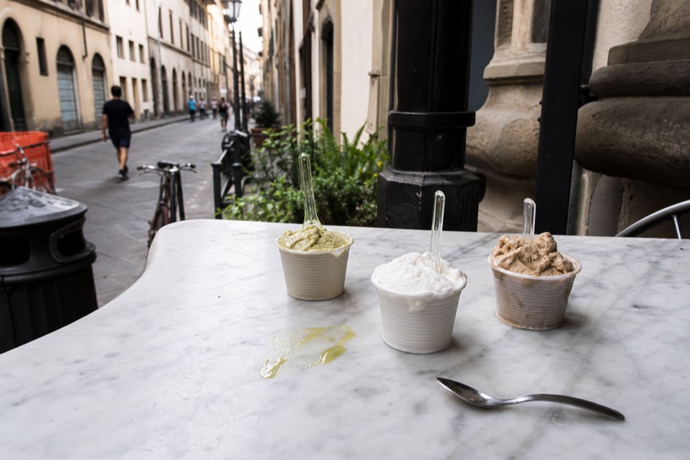 Cups of artisanal gelato on a marble gelateria counter, no text, no logos, no people