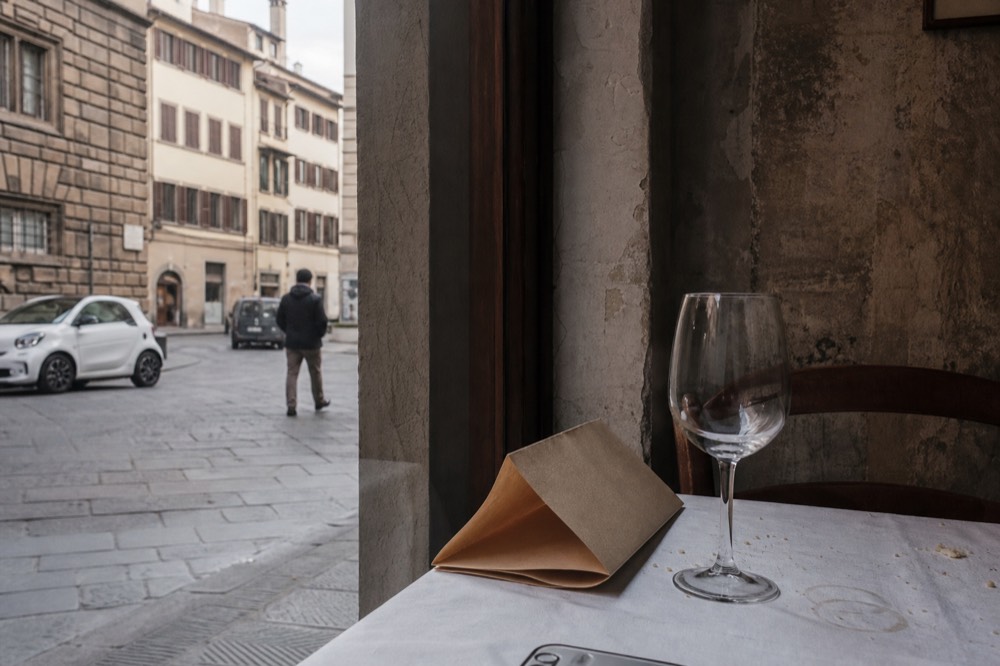 A paper restaurant menu on a set table beside a wine glass, no text, no logos, no people