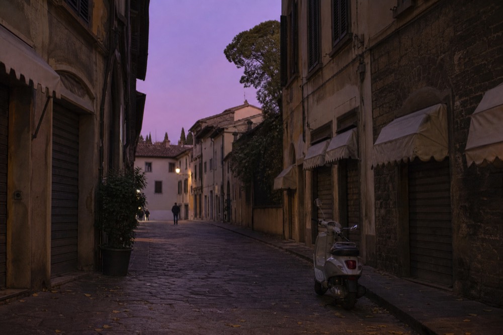 An empty Florentine street at dusk with restaurant awnings and shuttered windows, no text, no logos, no people
