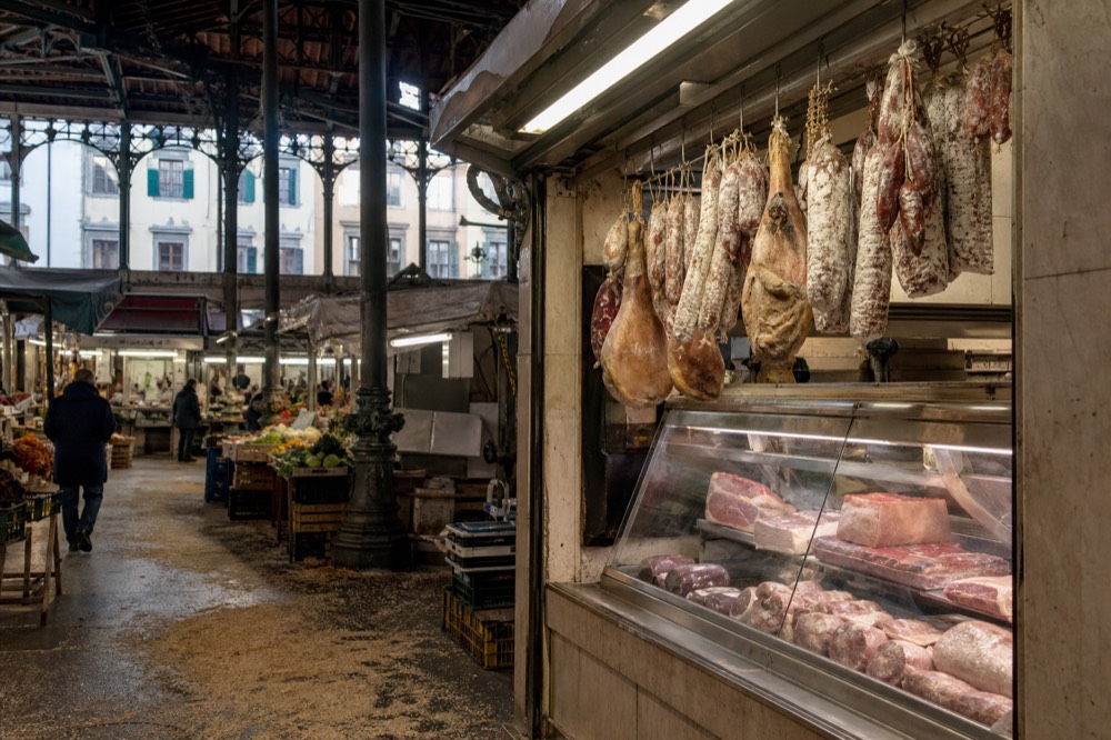 A Tuscan butcher shop counter with hanging dry-cured meats, no text, no logos, no people
