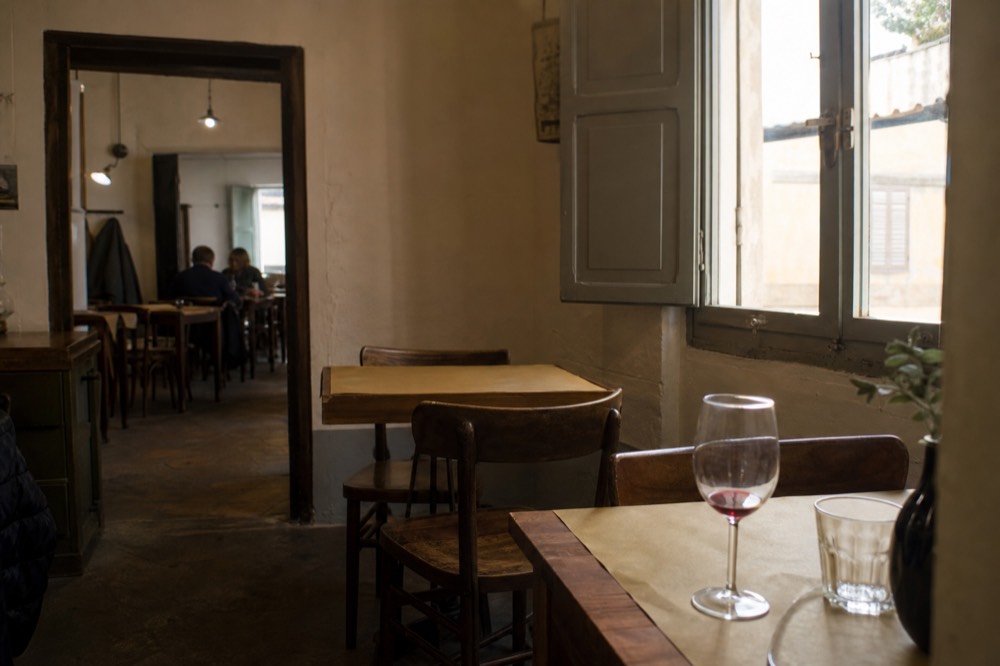 A small trattoria dining room with paper-covered tables and wood chairs, no text, no logos, no people