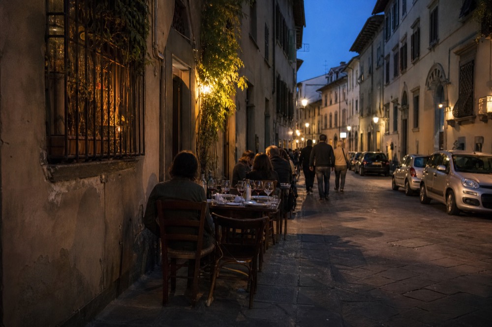 A Florentine dining table set with wine glasses and shared dishes at dusk, no text, no logos, no people