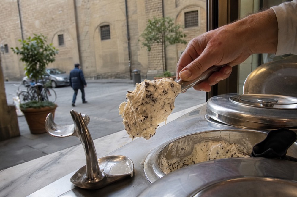 Gelato being scooped from a covered metal tub, no text, no logos, no people