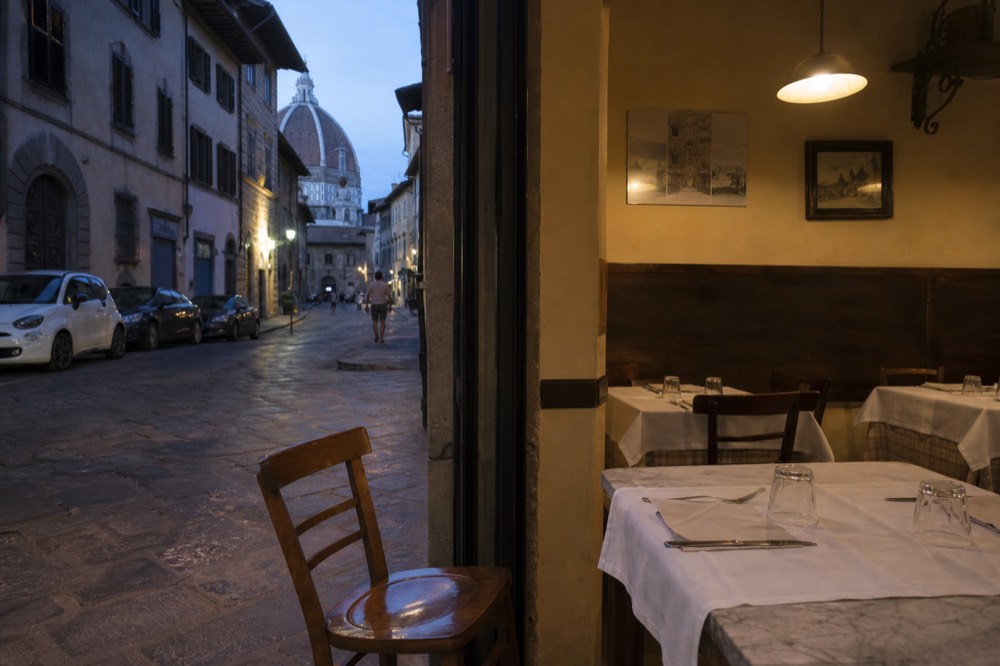 A small traditional trattoria dining room with marble-topped tables set for dinner, no text, no logos, no people