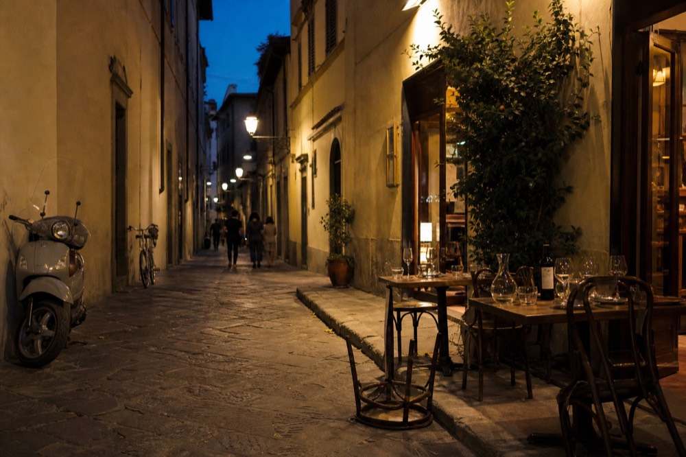 A Florence evening street with lit restaurants and wine bars, no text, no logos, no people