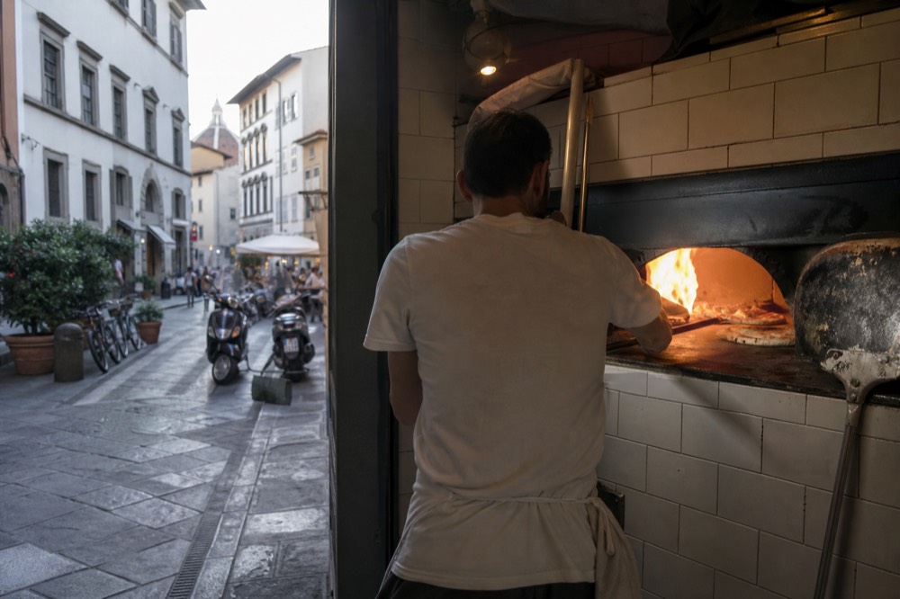 A pizzeria counter with pizzas coming out of an oven, no text, no logos, no people