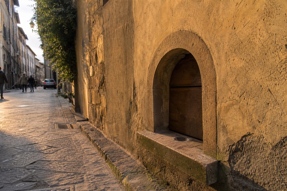 A stone wall with a small historic wine window opening, no text, no logos, no people