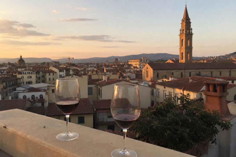 Two glasses of red wine on a terrace overlooking Tuscan hills at sunset, no text, no logos, no people