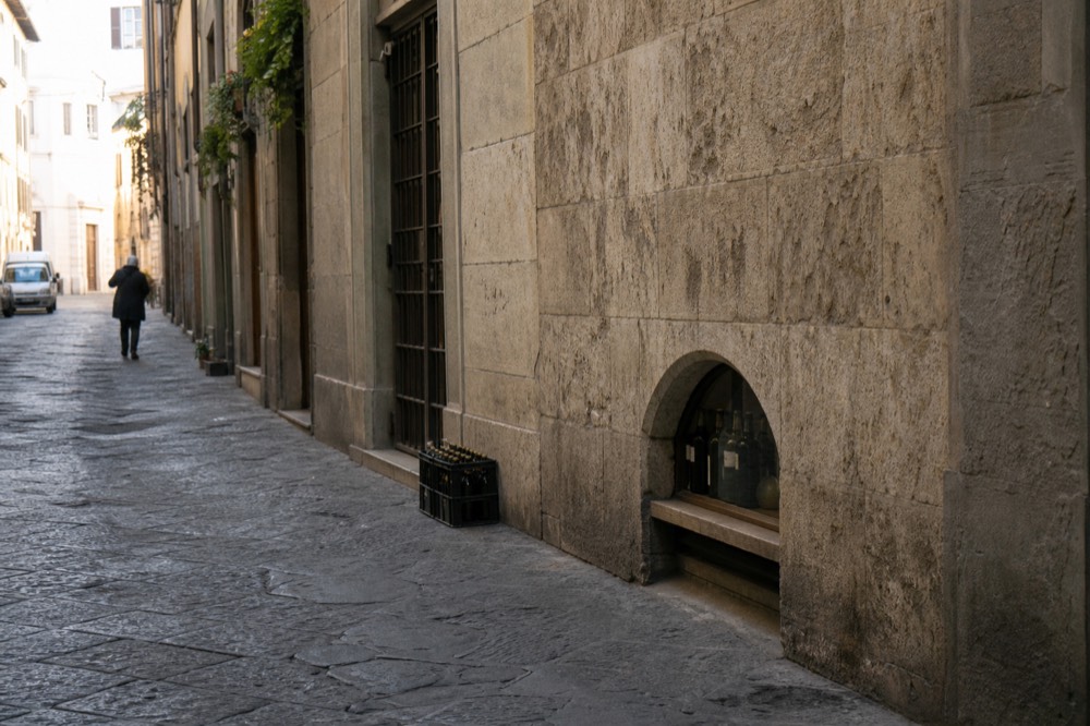 A narrow Florence street with an old stone palazzo wall, no text, no logos, no people