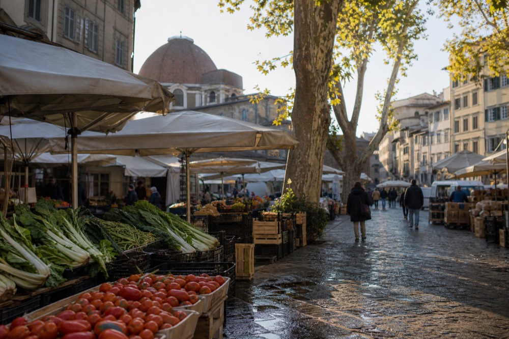 Outdoor stalls at Sant'Ambrogio market with fresh produce and shoppers, no text, no logos, no people
