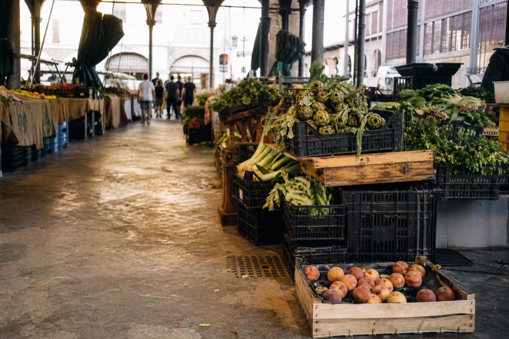 Wide shot of Sant'Ambrogio market interior with shoppers and stalls, no text, no logos, no people