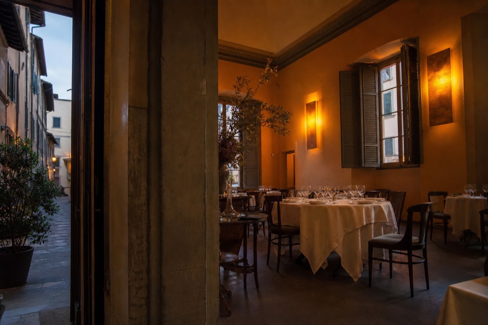 Refined dining room with set tables and warm lighting in a Florence fine dining restaurant, no text, no logos, no people