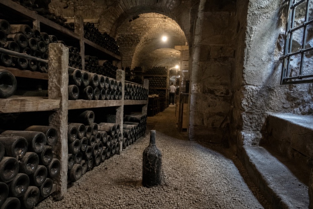 Historic wine cellar with racks of bottles beneath stone vaults, no text, no logos, no people