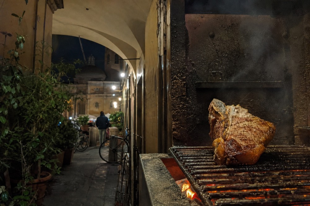 Thick Florentine T-bone steak grilled over charcoal flames, no text, no logos, no people