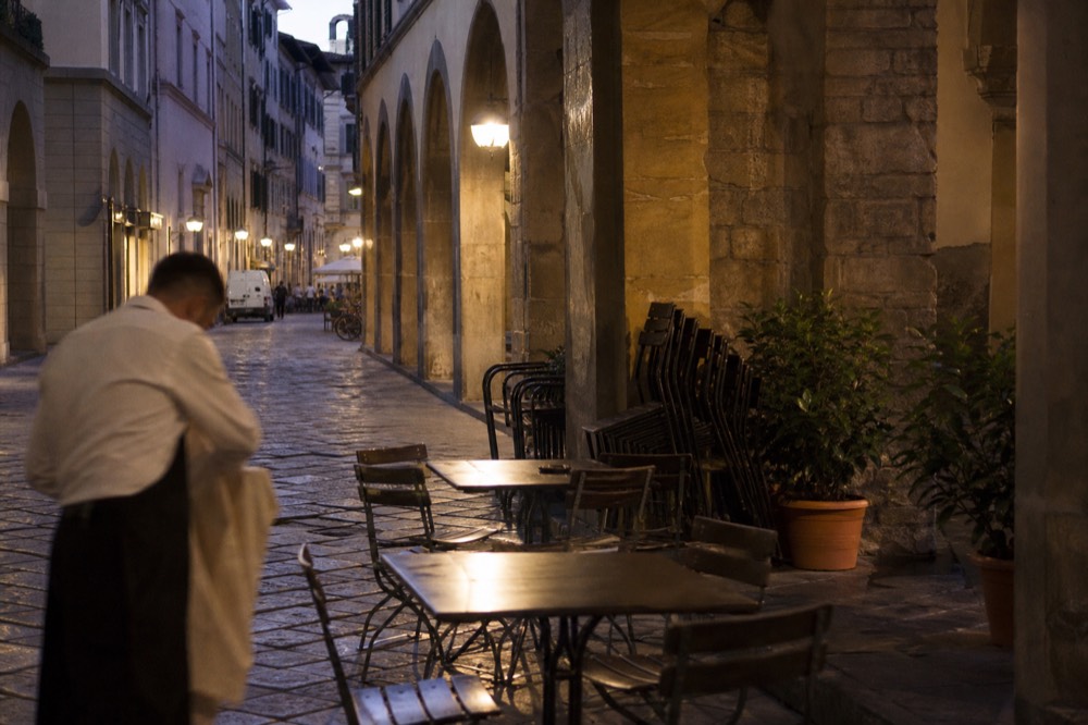 Outdoor tables on a Florence street in the evening, no text, no logos, no people