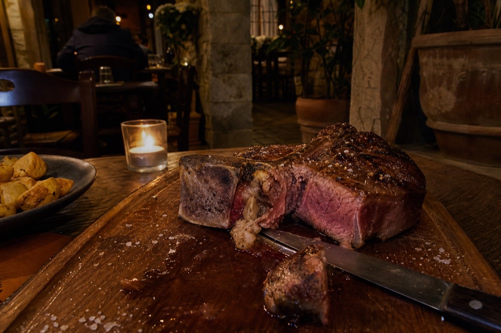 A thick grilled T-bone steak sliced open on a wooden board, no text, no logos, no people