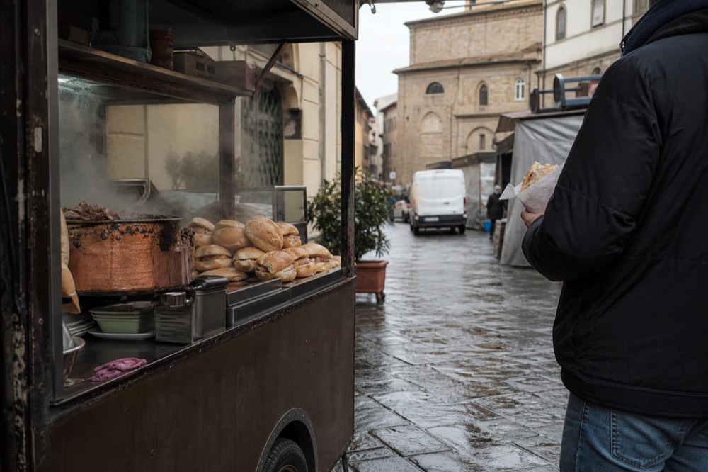 A street food cart serving lampredotto panini from a copper pot, no text, no logos, no people