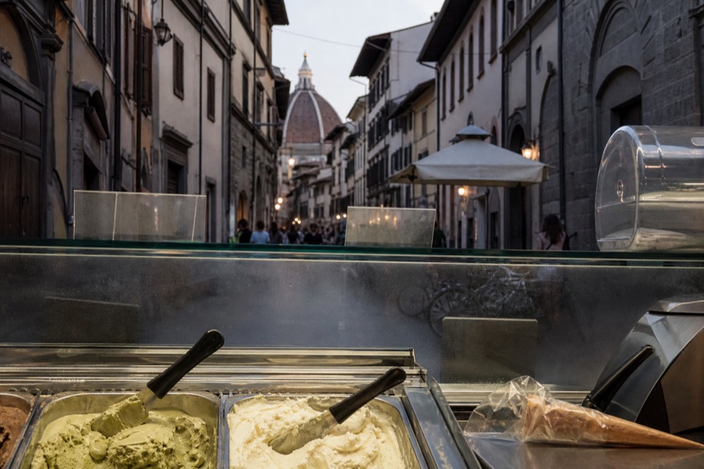 Artisanal gelato in metal tins in a small shop counter, no text, no logos, no people